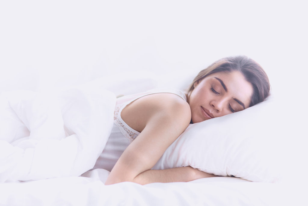 Chica durmiendo profundamente sobre sábanas blancas