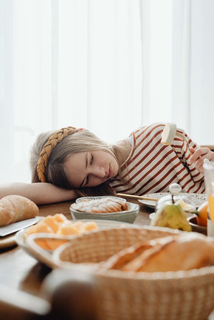 chica recostada sobre mesa llena de comida