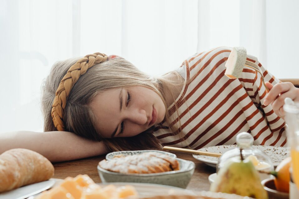 chica recostada sobre mesa llena de comida