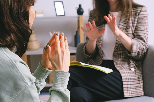 mujer en terapia con psicóloga explicándole algo con las manos