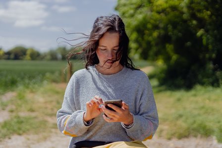 chica en el campo mirando el móvil