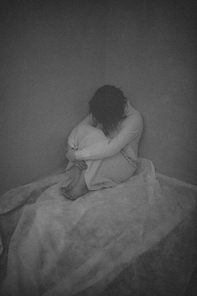 imagen en blanco y negro de persona agazapada en la cama sufriendo depresion