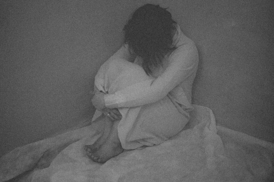 imagen en blanco y negro de persona agazapada en la cama sufriendo depresion