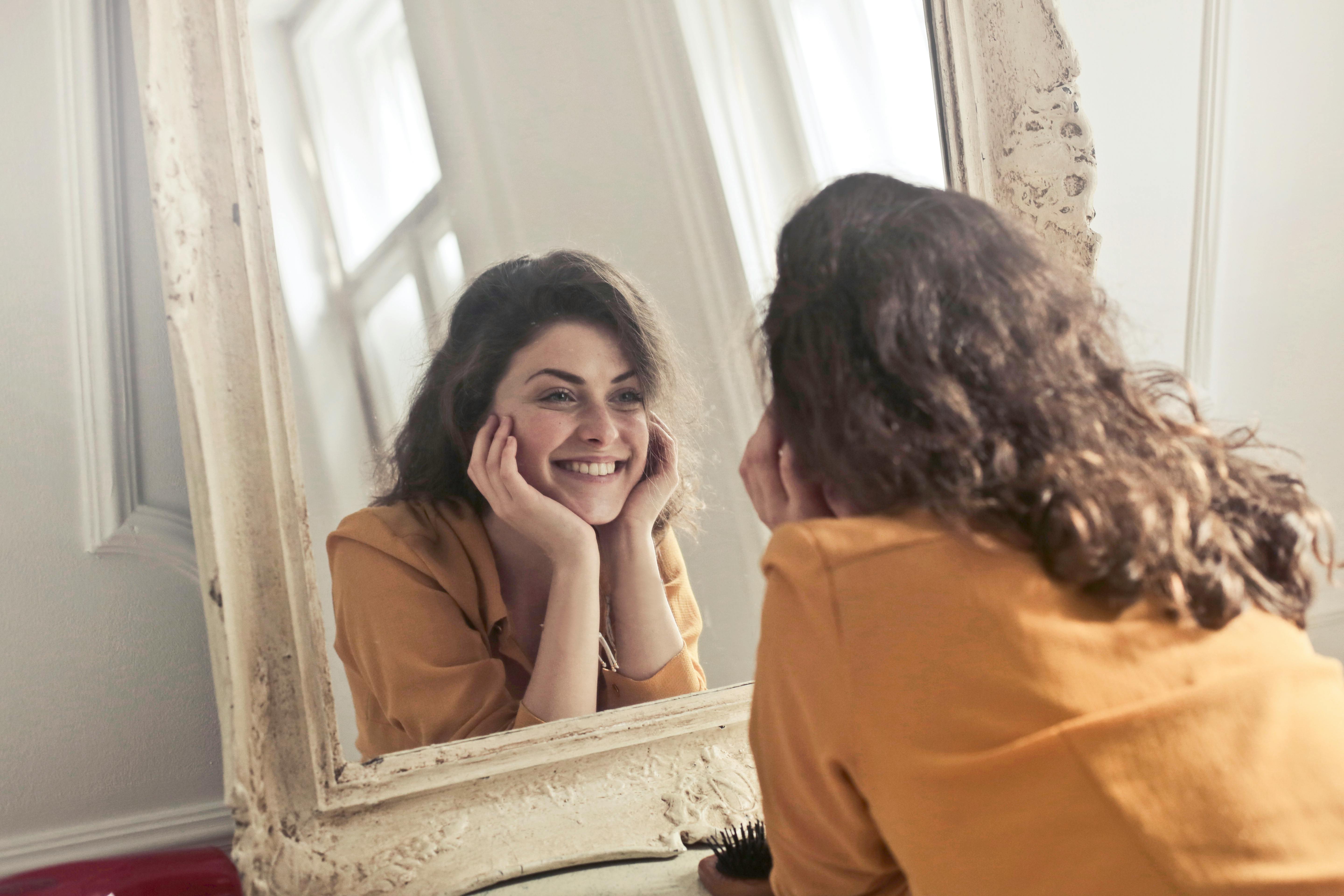 mujer joven se observa en el espejo y sonrie