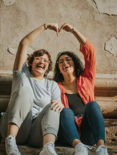 dos mujeres haciendo un corazón con las manos y sonriendo