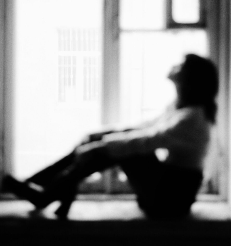 mujer sentada mirando por la ventana en blanco y negro